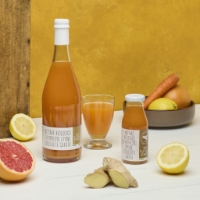 Nettare Bio Di Pompelmo, Limone, Zenzero E Carota 750ml, frontale due formati con ingredienti su tavolo