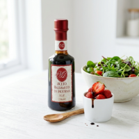 Mo Aceto Balsamico di Modena IGP su tavola frontale con fragole e salad