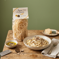 Pici al tartufo frontale su tavolo con piatto condito