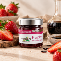 Chutney di fragole e aceto balsamico, in barattolo e su una tavola con fragole e una bottiglia di aceto balsamico